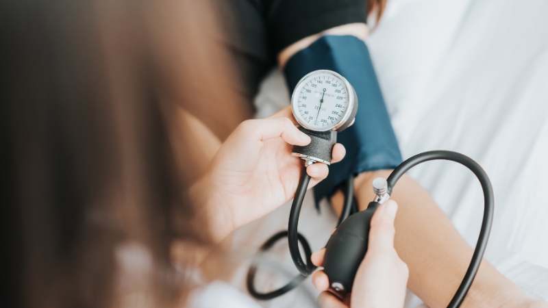 A person checks someone's blood pressure with a manual cuff, highlighting the importance of monitoring for stroke risk