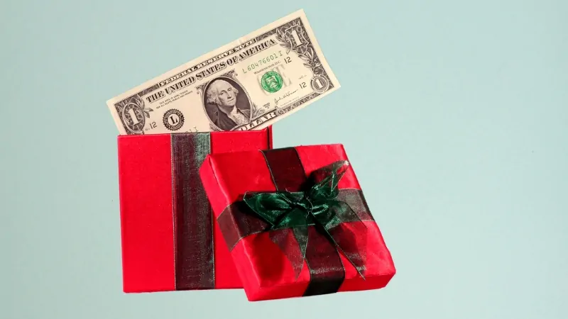A red gift box with a dollar bill sticking out, symbolizing how much Americans spend on gifts each year