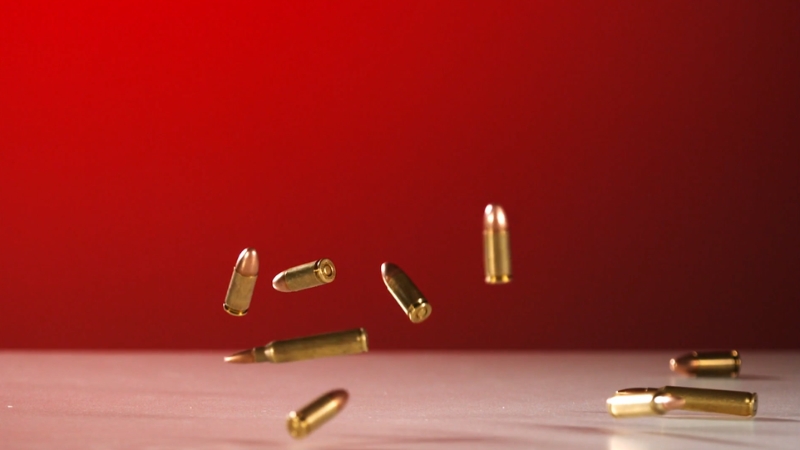 Bullets fall onto a white surface against a red background