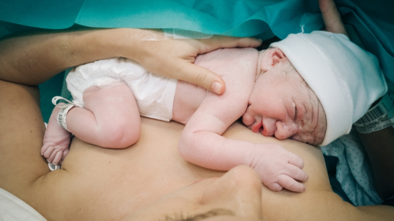 A newborn lies on a mother’s chest after delivery, capturing the reality behind teen nonmarital birth rates