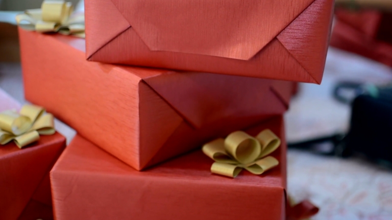 A stack of red gift boxes with gold bows shows the variety of gifts Americans are buying