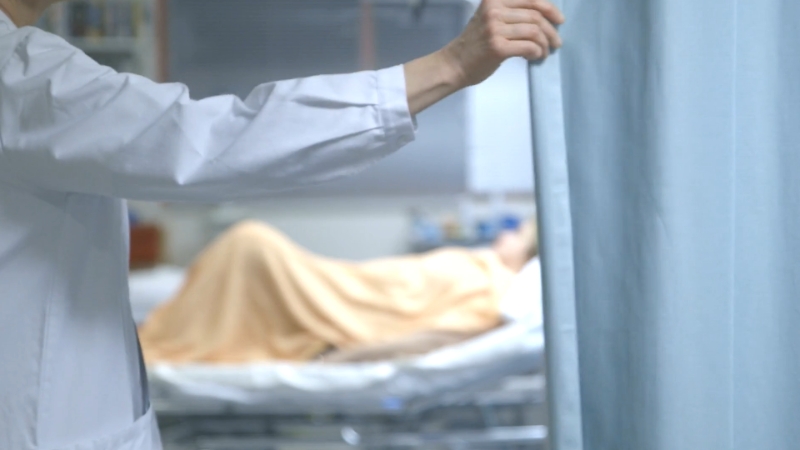 Doctor closing a curtain in a hospital room, focusing on patient privacy and care in German hospitals