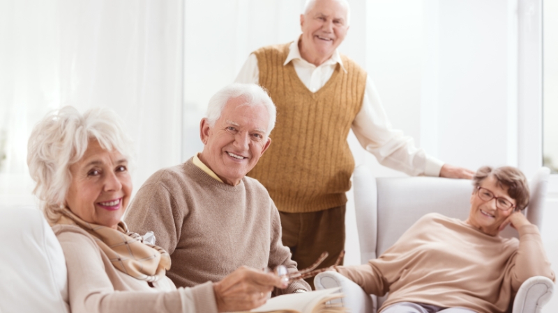 A group of smiling seniors sits together in a bright room, reflecting on the average retirement age in the United States