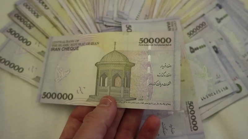A hand holding a 500,000 Iranian Rial banknote