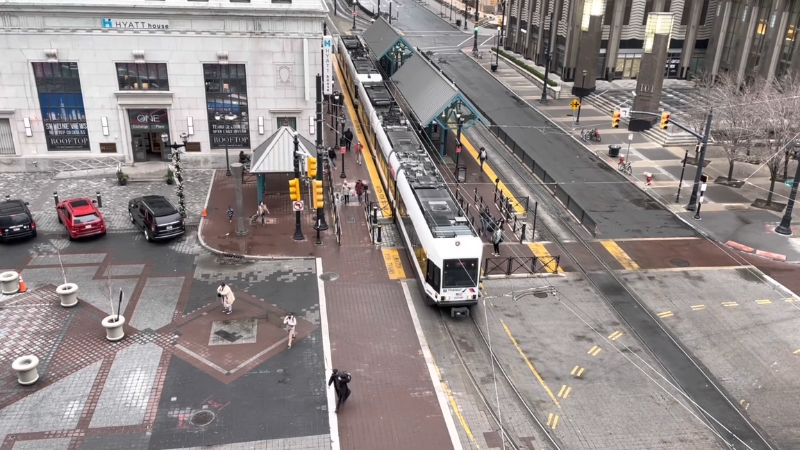 A light rail train stops at a platform in downtown Jersey City near the Hyatt House hotel