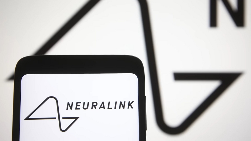 A smartphone displays the Neuralink logo in front of a larger version of the same logo