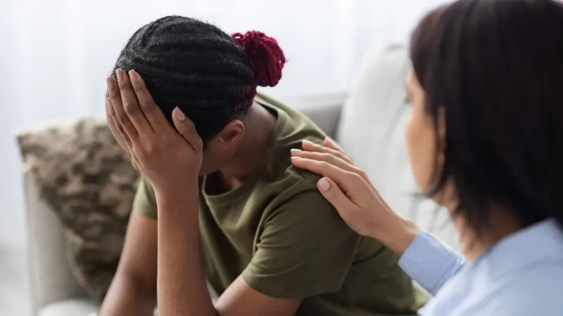 A woman receives support from a therapist during a PTSD treatment session