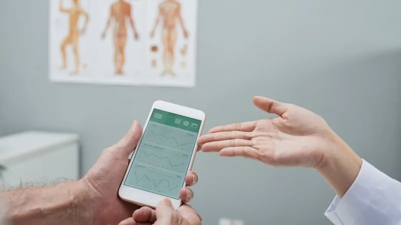 A doctor shows a patient health charts on a smartphone, explaining how data helps guide care decisions