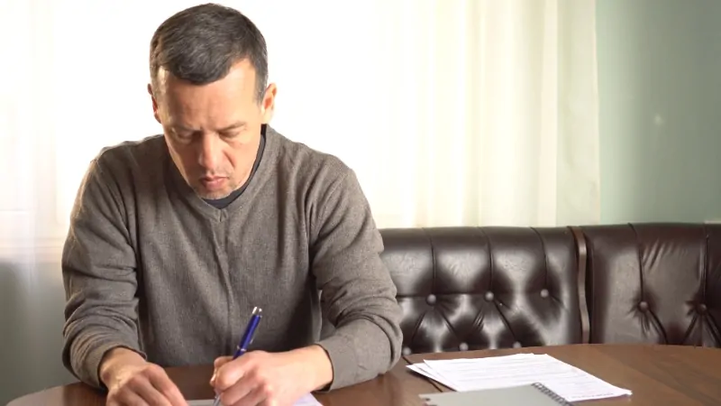 A man reviews loan documents at a table, dealing with the highest interest charges in the US