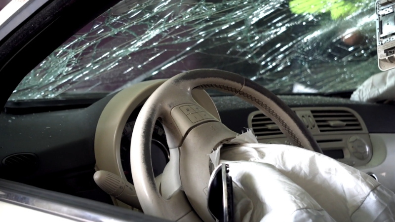 Deployed airbag and shattered windshield inside a crashed car