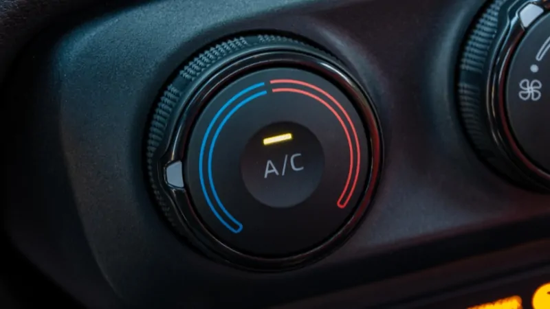 Close-up of a car’s A/C temperature control knob, showing the cooling and heating range