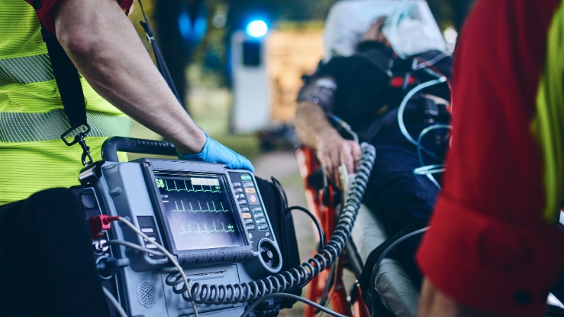 Paramedics rush a patient to the hospital while monitoring vital signs on emergency equipment