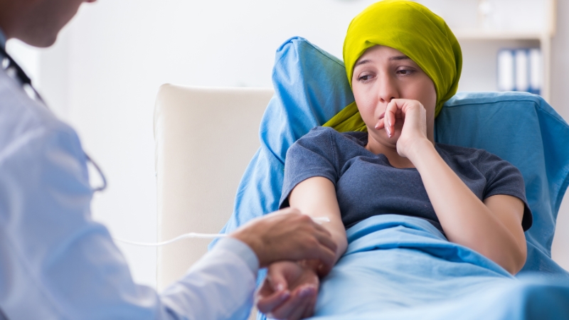 Doctor treating a woman with cancer in a hospital bed, reflecting geographic disparities in cancer rates
