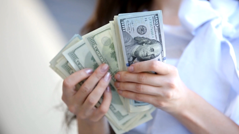 A person holding several stacks of US dollar bills