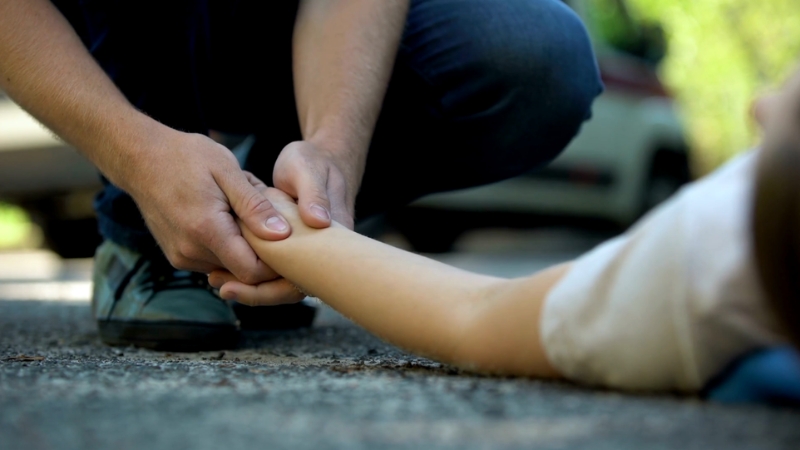 A person checks the pulse of a crash victim on the road, reflecting Louisiana’s high car accident fatality rates