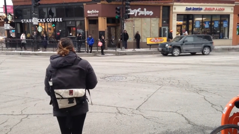 A pedestrian waits to cross at the Milwaukee–North–Damen intersection