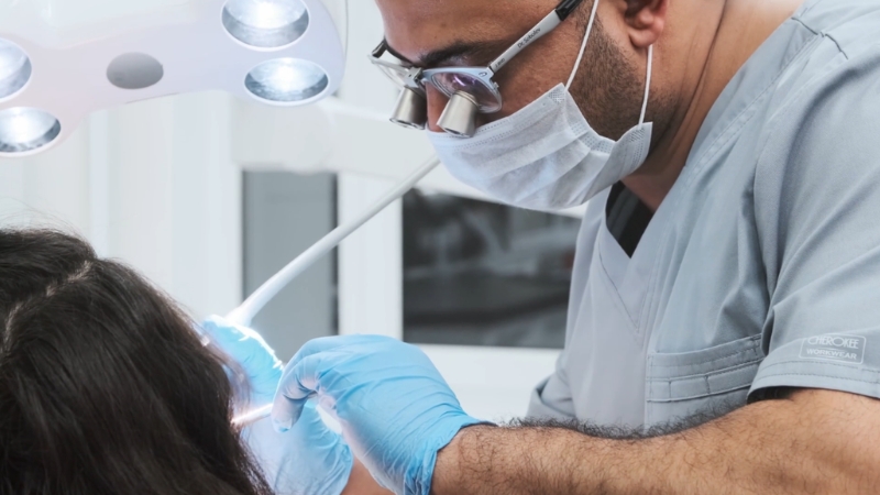 Dentist in protective gear treating a patient, illustrating national benchmarks for dental care costs
