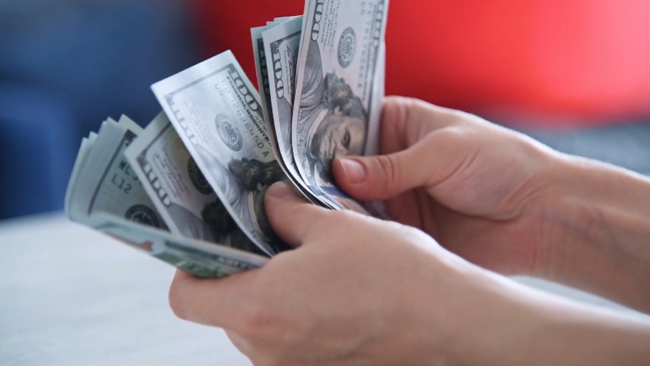 A person counts U.S. dollar bills by hand