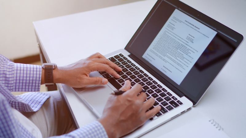 A person typing on a laptop with a health-related article open on the screen