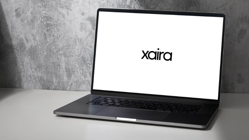 A laptop screen displays the Xaira Therapeutics logo on a plain white background