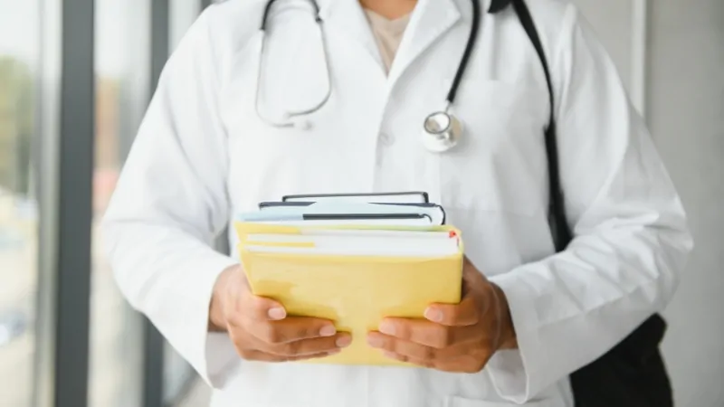 A doctor holds medical records, symbolizing the role of GPA and MCAT scores in medical school admission
