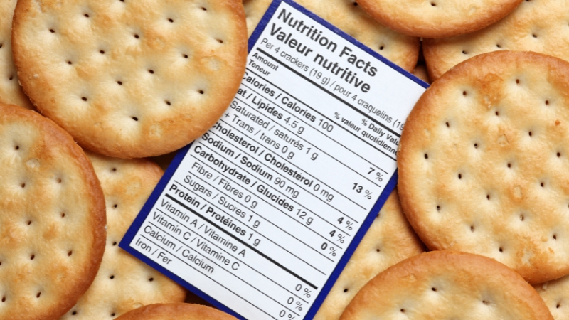 A nutrition label rests on top of several round crackers, showing calories, fat, and other values