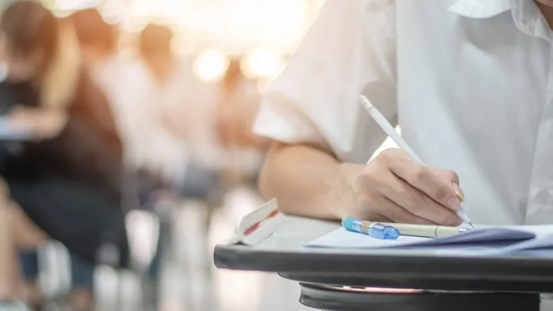 A student takes an exam, reflecting GPA and MCAT averages that shape medical school admission standards