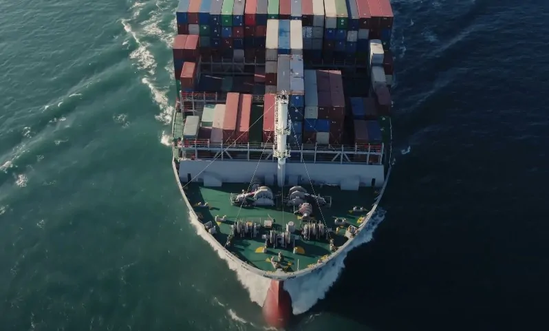 Aerial view of a large container ship navigating through the deep blue ocean waters