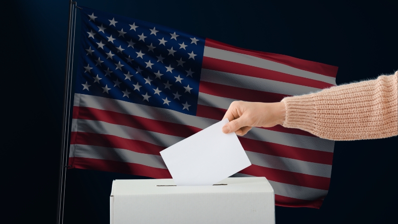 A person casts a ballot into a box in front of the U.S. flag, representing high voter registration across top-performing states