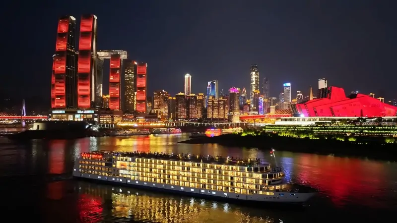 A river cruise ship passes Chongqing’s glowing skyscrapers at night