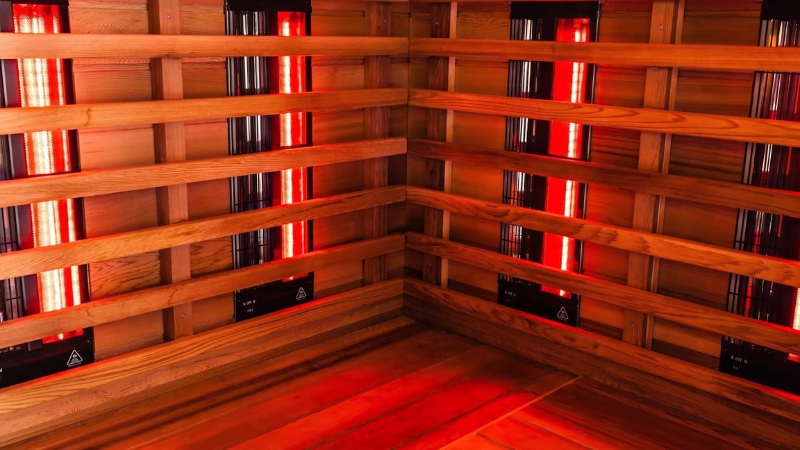 Infrared heater panels inside a wooden sauna glow red across both walls