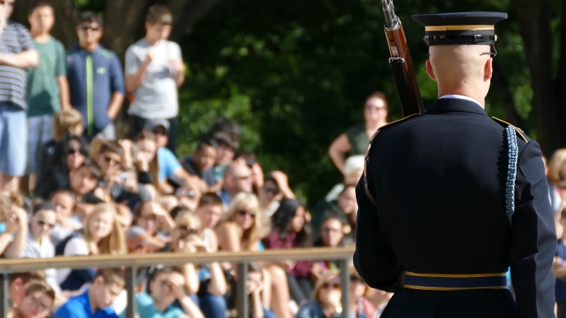 A uniformed soldier stands before a crowd during a Memorial Day ceremony