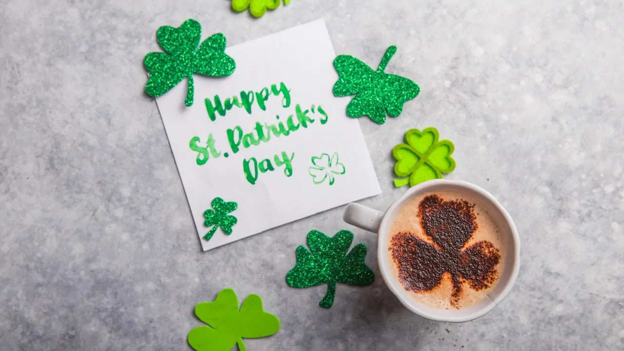 St. Patrick’s Day card and shamrock decorations sit beside a coffee cup with a clover design
