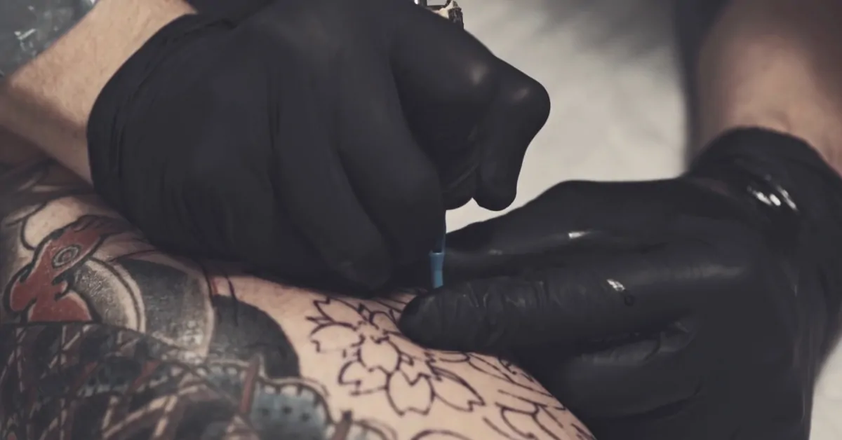 Tattoo artist works on detailed ink, highlighting the focus on tattoos and cancer