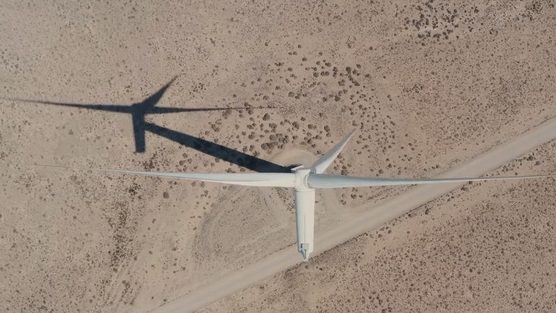 A wind turbine stands in a dry Texas landscape viewed from above
