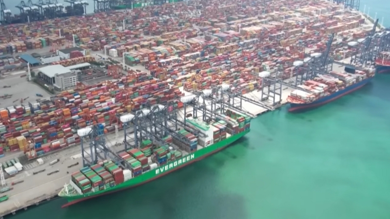 Aerial view of a busy shipping port with containers and ships, highlighting global trade impacted by U.S.-China trade tensions