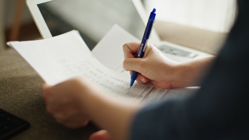 Person reviewing costs on printed papers with a pen to illustrate calculating a wedding budget