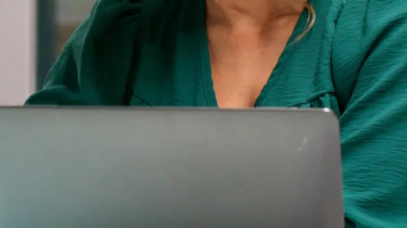 A person in a green blouse works quietly on a laptop, capturing the focused atmosphere of this week's work in the newsroom