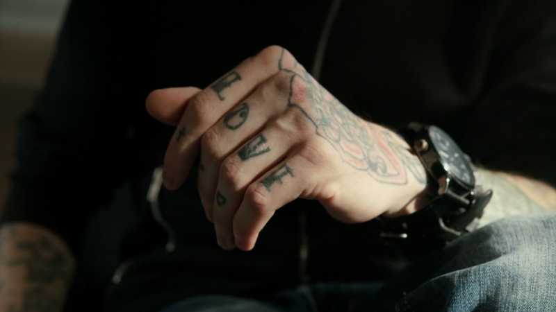 Tattooed hand rests in natural light as the topic of cancer risk is explored
