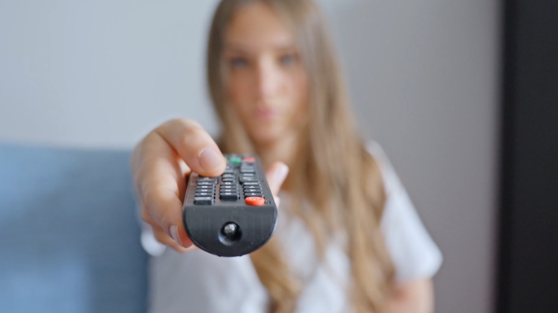 A woman points a TV remote toward the camera in a living room
