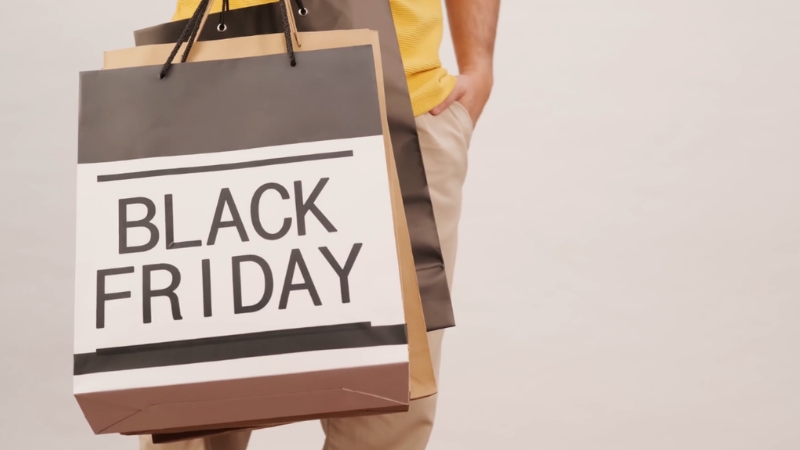 A shopper holds large bags marked black friday during a busy sale day
