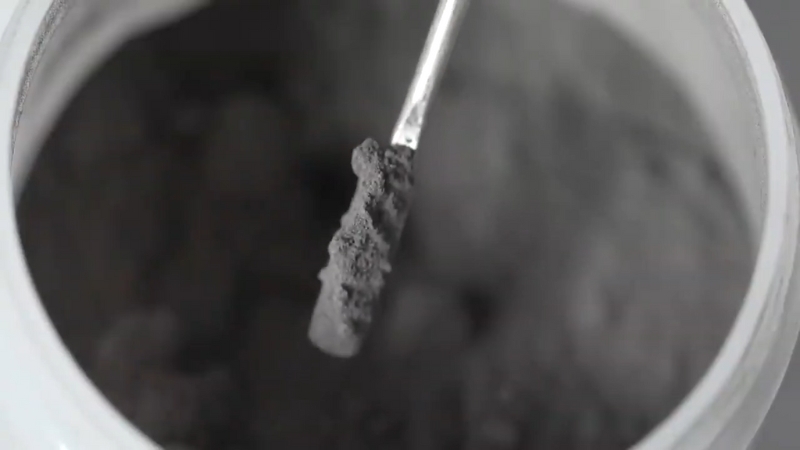 Coal ash powder lifted on a small metal scoop inside a container