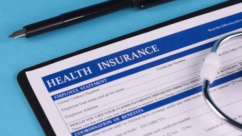 Health insurance form with a pen and stethoscope, linked to state health insurance mandates in 2025