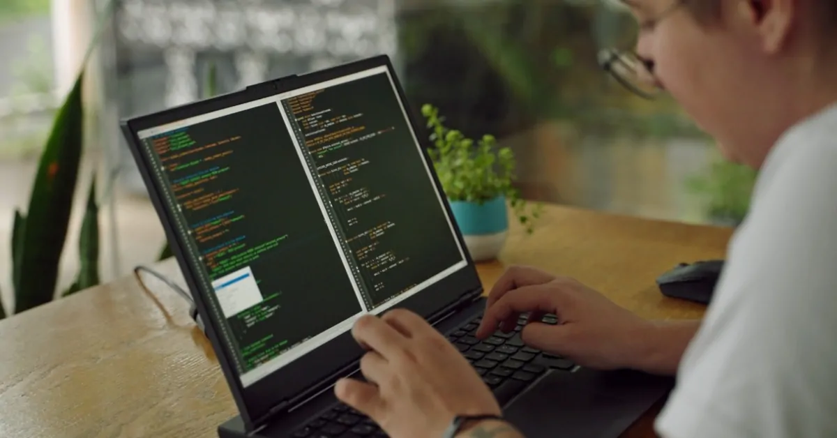 Person writing code on a laptop at a desk, representing software jobs growth