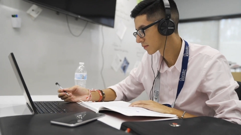 Bentonville Ignite student at a laptop with notes and headphones during a project-focused class session