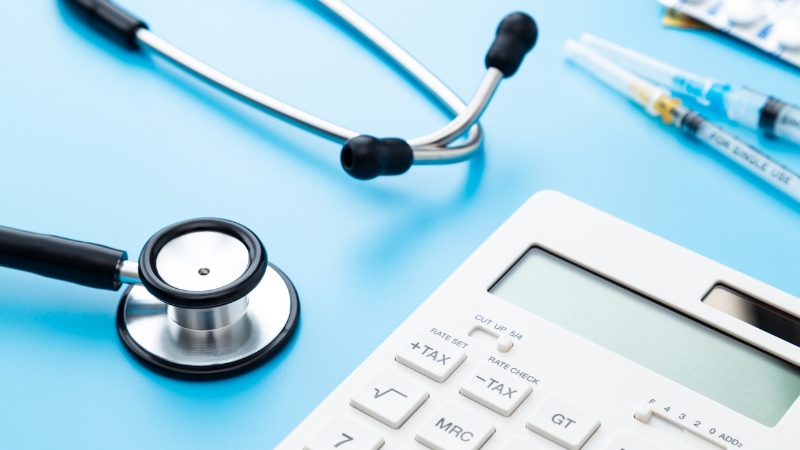 Calculator and stethoscope on a desk represent a medical expense reimbursement plan setup