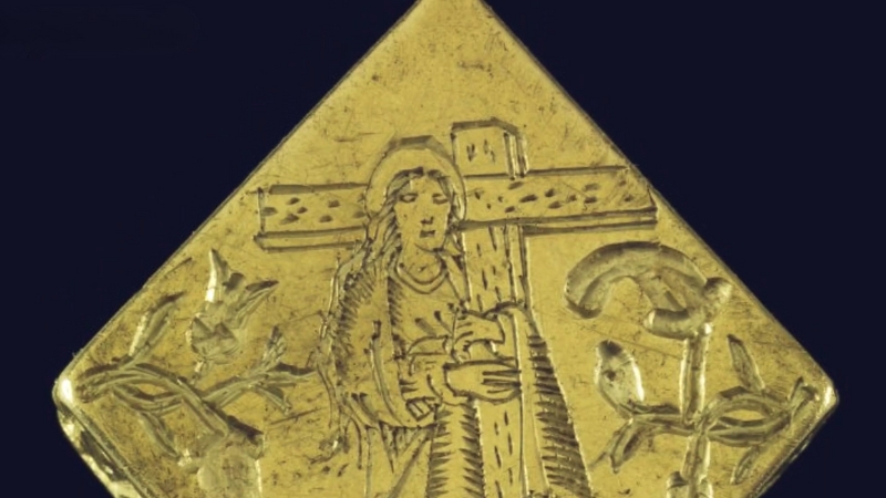 Close-up of a Tudor-era gold pendant engraved with a female saint holding a cross