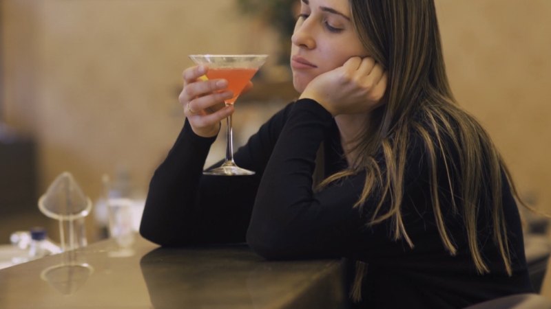 Woman sits with a cocktail to reflect alcohol use and breast cancer risk