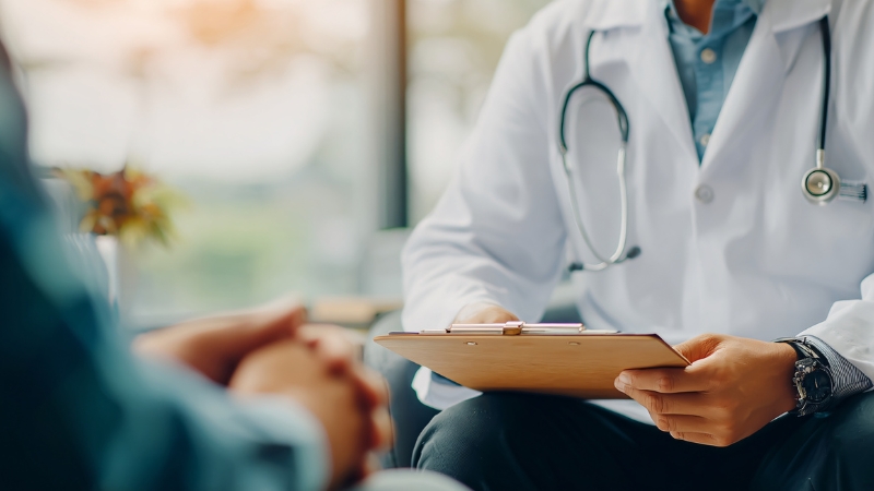 Doctor reviewing notes during a patient visit, reflecting differences in healthcare use between men and women