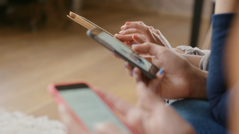 People sit together and scroll on smartphones while reading and watching digital content